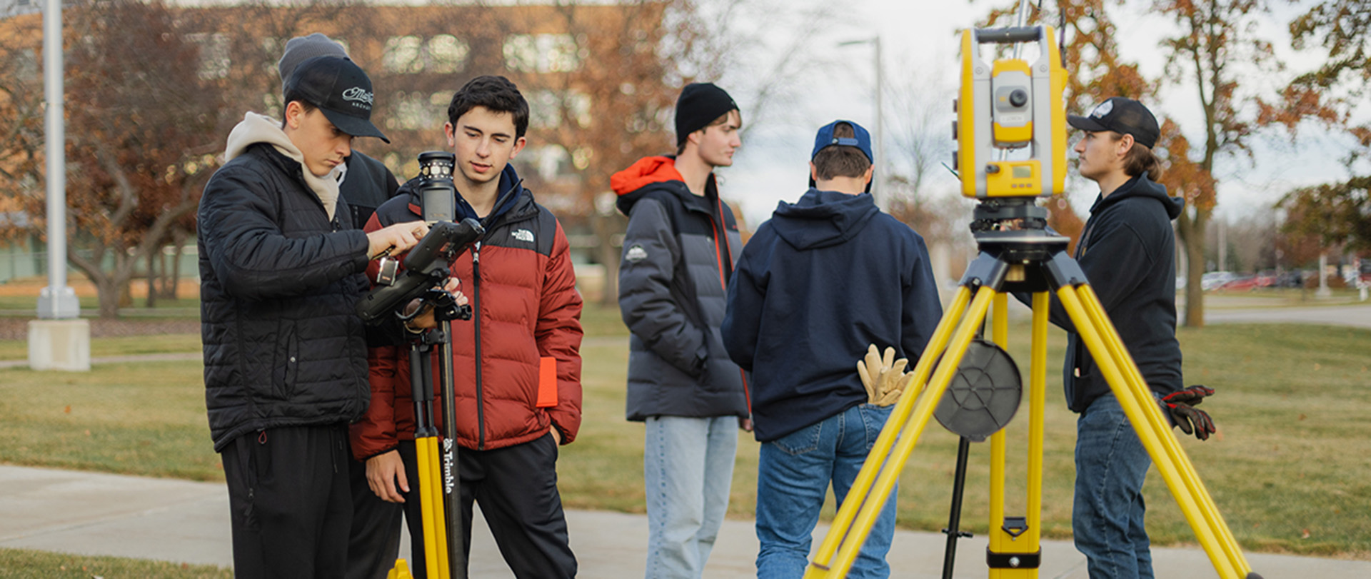 A group of Ferris State University Surveying Engineering students using surveying robotic total stations during an outdoor lab on campus.