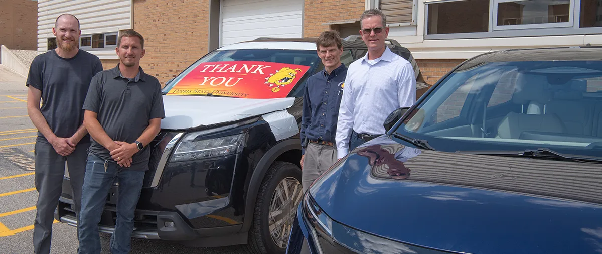 four men standing around two cars