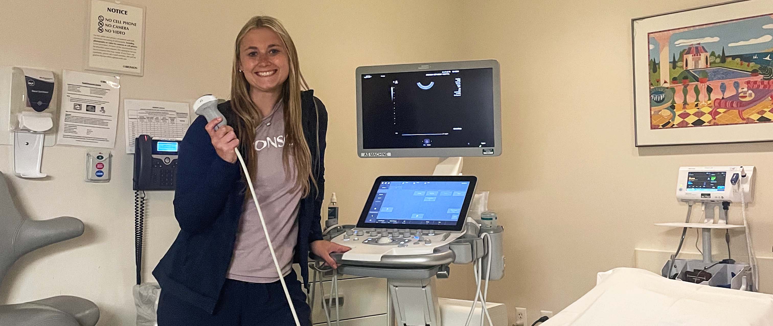 Payton Stahl next to diagnostic medical sonography equipment.