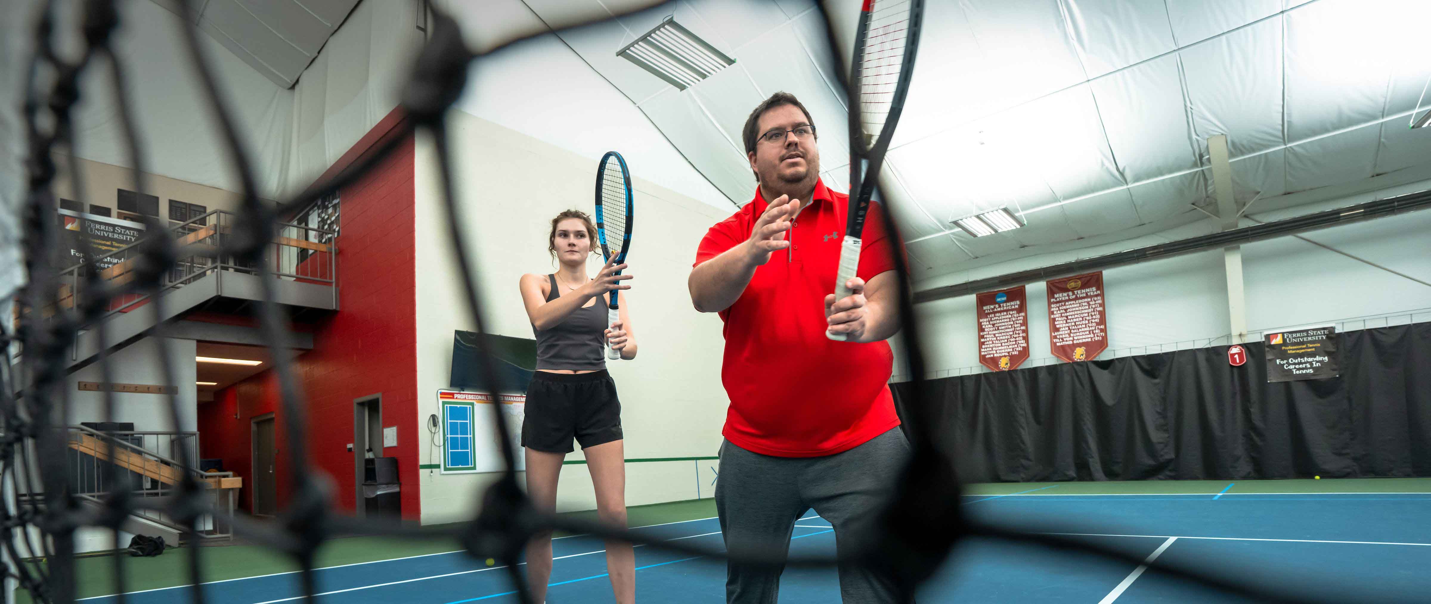 Michael Janz, Assistant Director of Ferris State University’s Professional Tennis Management, and a student during instruction on the court.